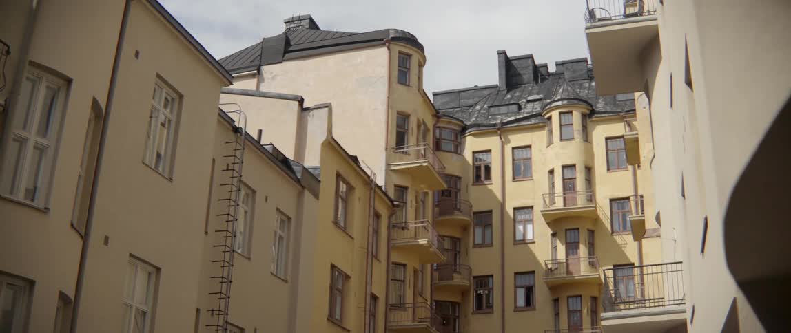 Traditional European residential blocks stand close together under a grey cloudy summer sky.
