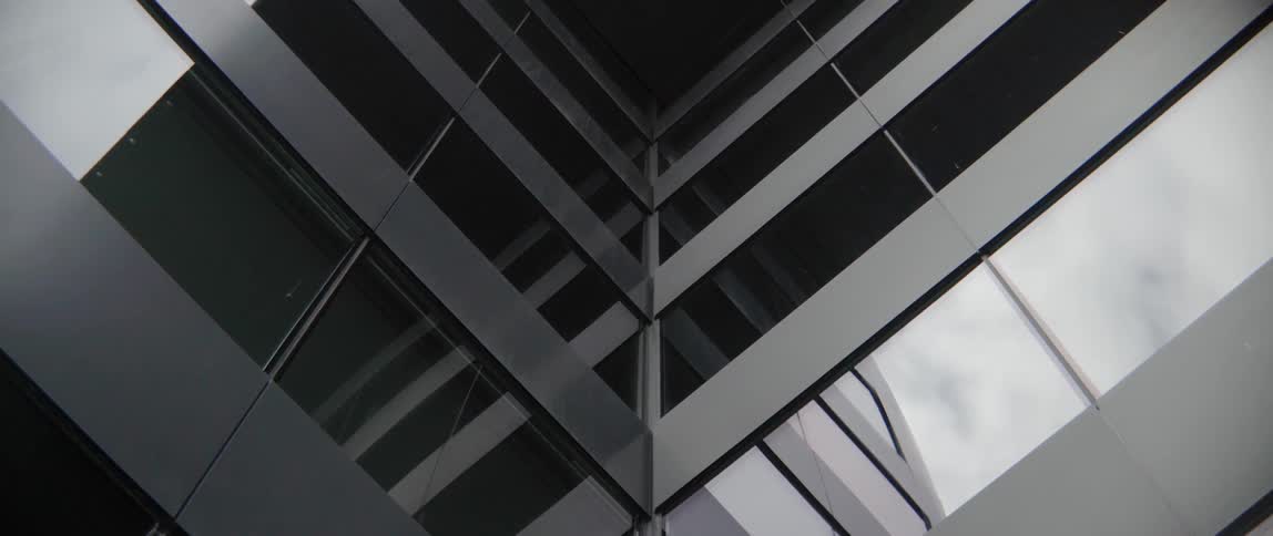 Shiny glass panels on a contemporary skyscraper reflect architectural lines under daytime sky.
