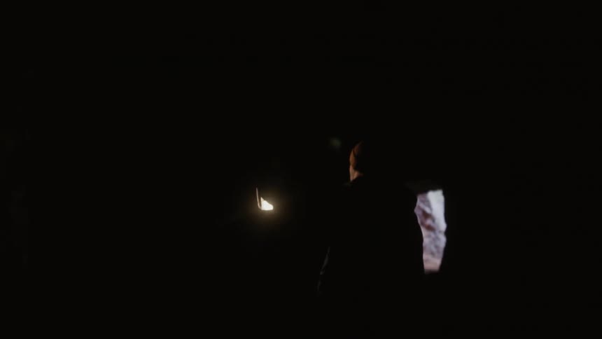 Person walks through a cave holding a lantern