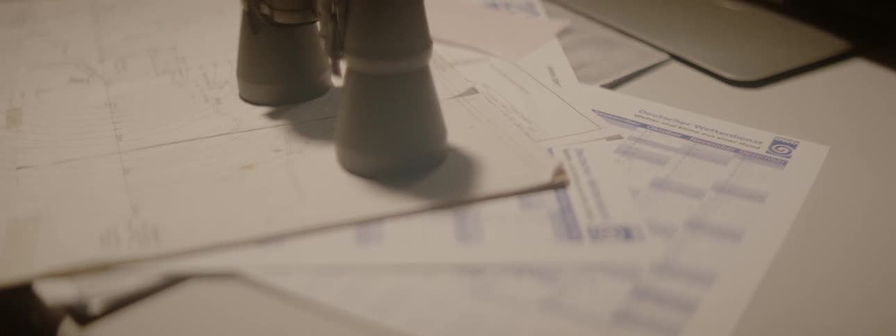 Binoculars standing up on papers cast a swaying shadow