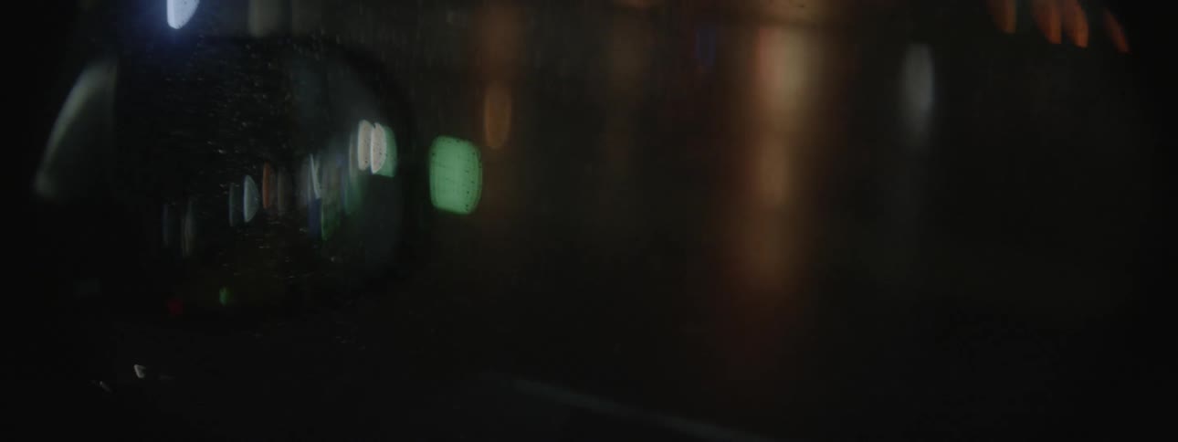 The street is passing by outside a car window at night