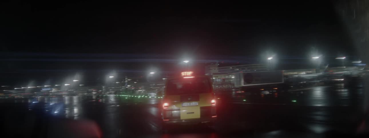 An airport vehicle is traveling across the tarmac at an airport at night