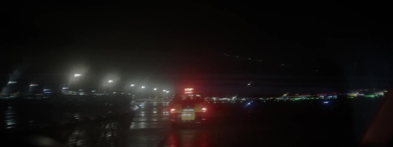 A truck drives on a wet airport road at night