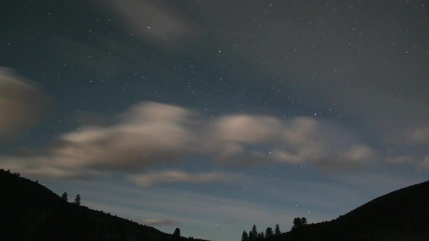 White clouds travel over the rolling hills as the sun sets