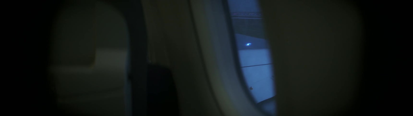 The runway is passing outside an airplane window as it takes off