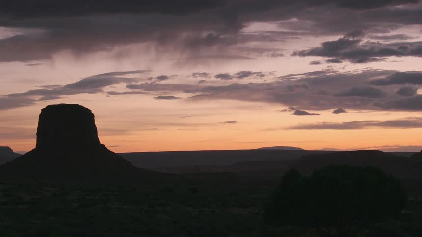 A large hill sits to the left at sunset on a cloudy day