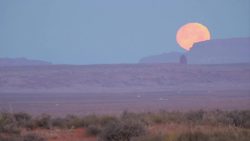 Timelapse of the moon setting behind a mountain