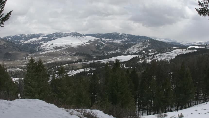 Time lapse of storm clouds moving over snow covered mountains