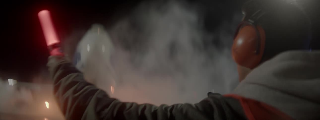 An airport worker signals with light batons at night