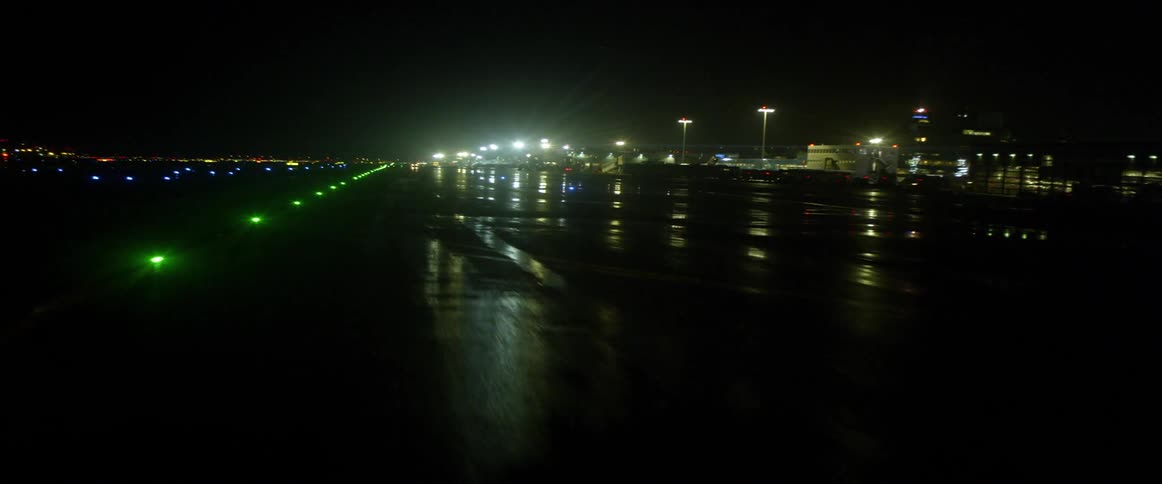 An airplane is traveling down a runway at night