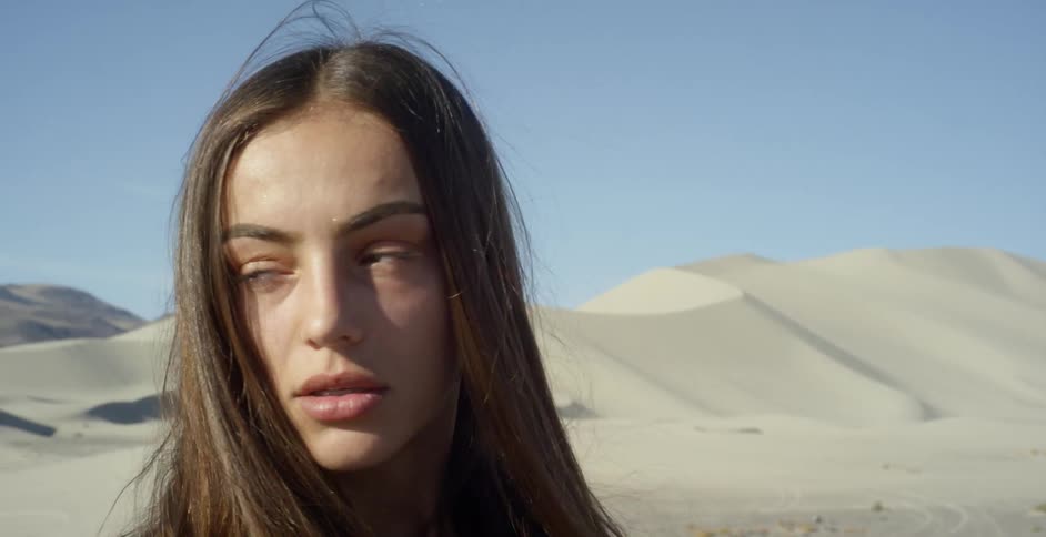 A woman stands in a sandy desert