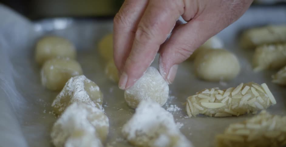 Person putting ball of dough on cookie sheet,