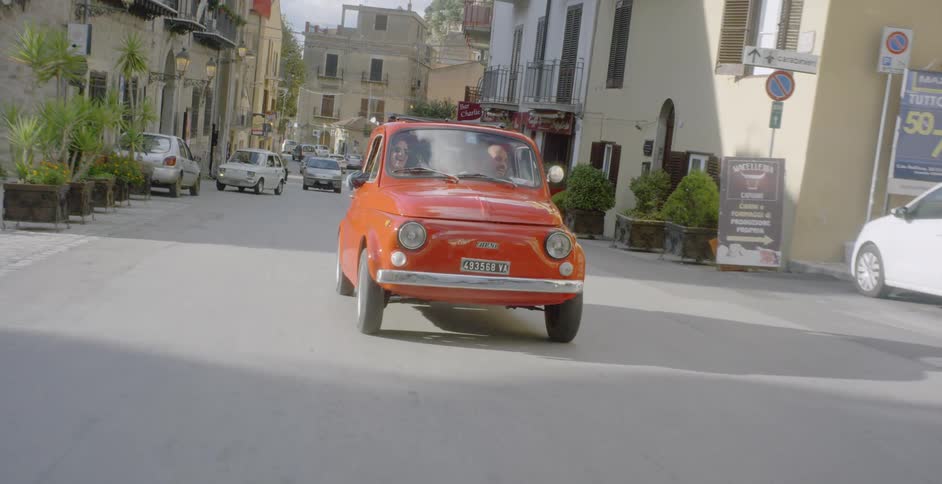 Red car drives down a busy city street