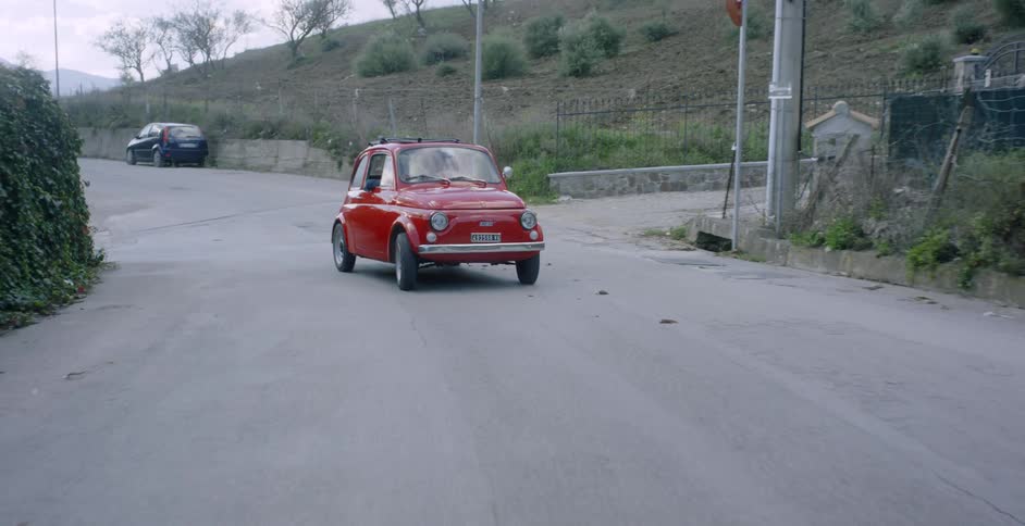 A couple are driving in a car in a rural european village in daylight