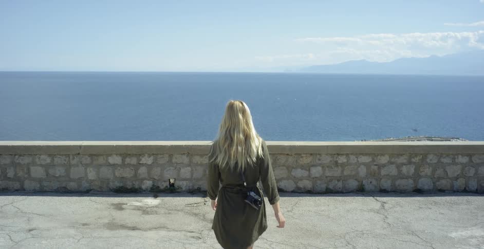 Woman walks near a ledge overlooking at large body of water