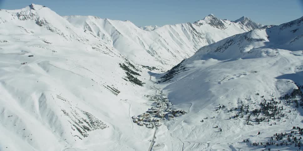 Sun shines down on snowy mountains with K��htai village