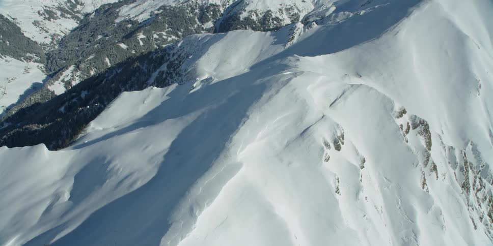 Snow is covering the slopes of a mountain range during the day