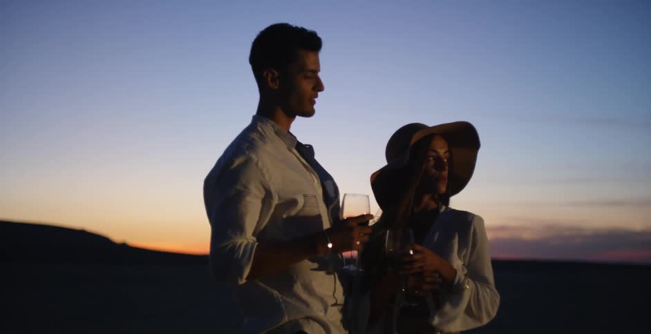 A man and woman drink wine at dusk