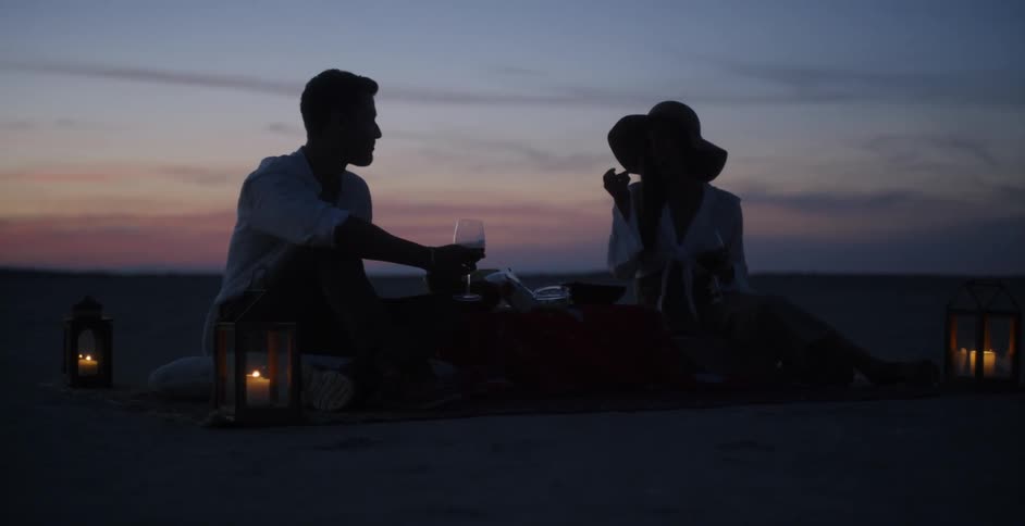 A man and woman picnic at dusk