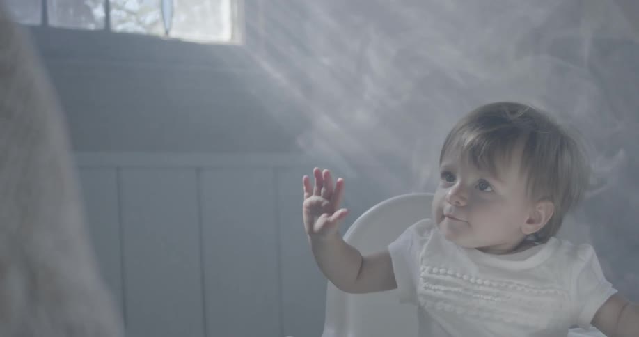 A baby is sitting in a highchair flailing its arms