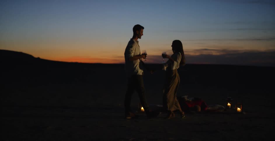A couple dance in the sand at sunset