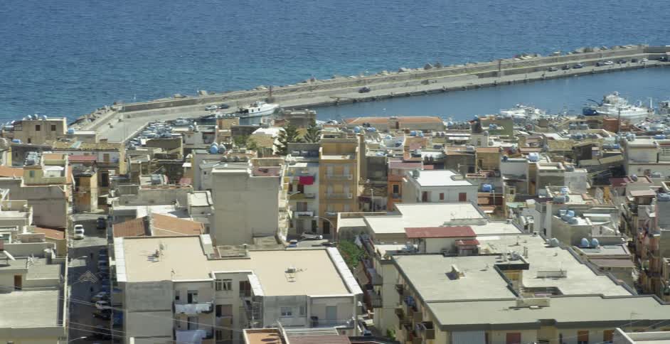 An old world village spreads out along an ocean shoreline in daylight