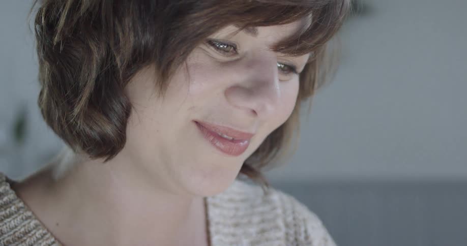 A woman smiles and talks as she looks down
