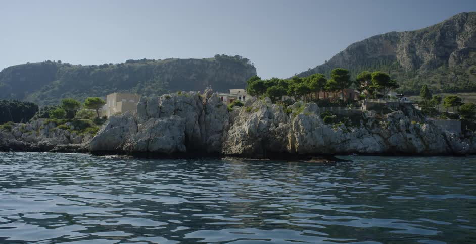 The waves are crashing against the tall rocks by the island