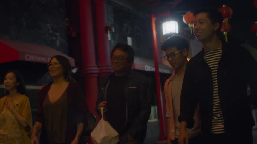 Group of smiling people walk through a city at night