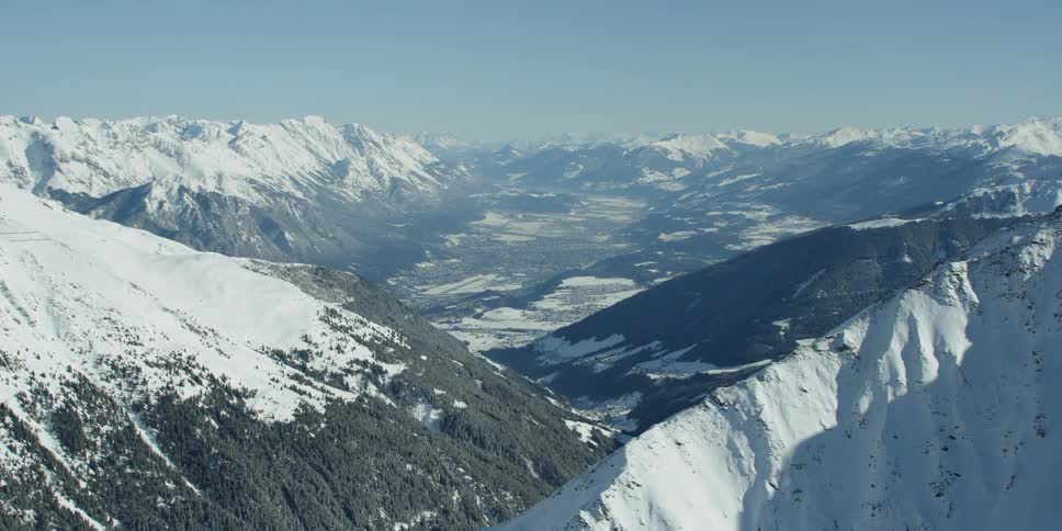 Snow covers the mountain landscape with the city Innsbruck in the background