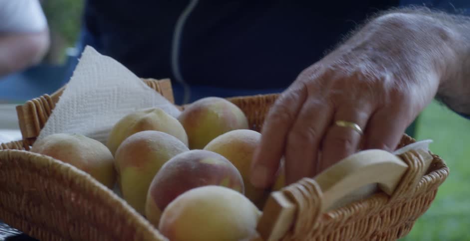 A man picks through a basket of peaches