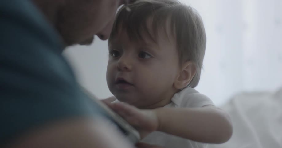 A man is holding his child in the dark bedroom