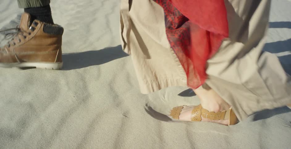 Man and woman are walking in thick sand on sunny day
