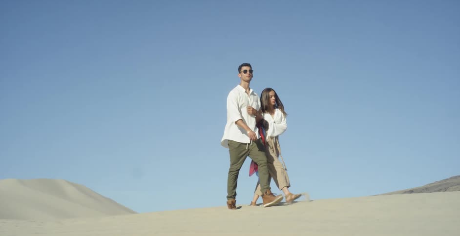 Man and woman walking in a desert-like area on a clear day