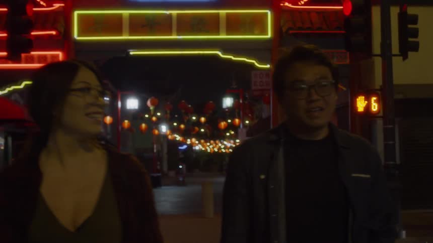 A man and woman walk in the city at night