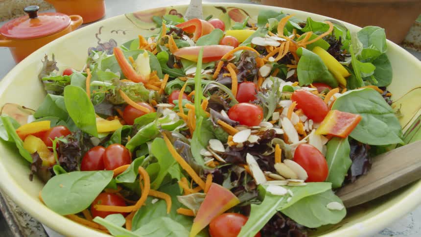 Salad in a large bowl on a table near small pots