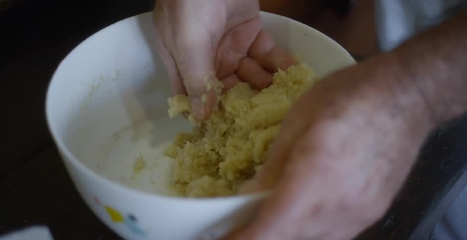 A man mixes food by hand in a bowl