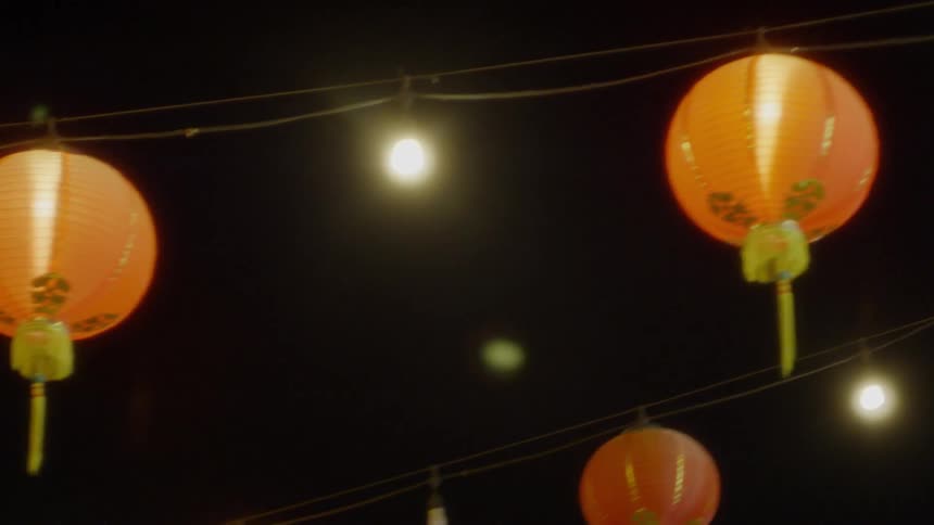Orange chinese lanterns hang on a line outside at night