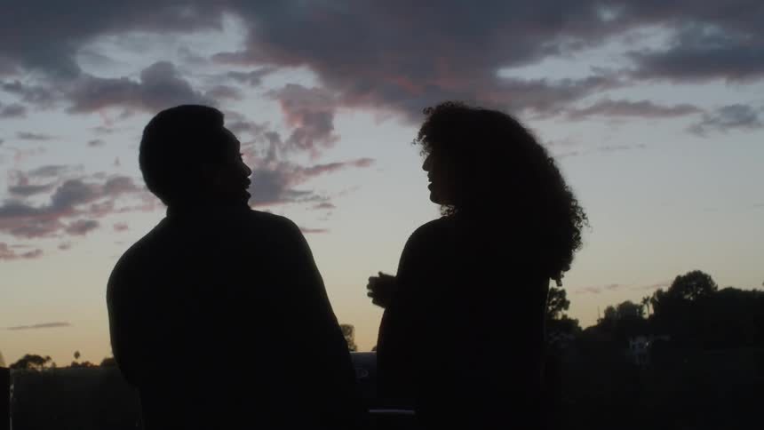 Man and woman talk outside at sunset