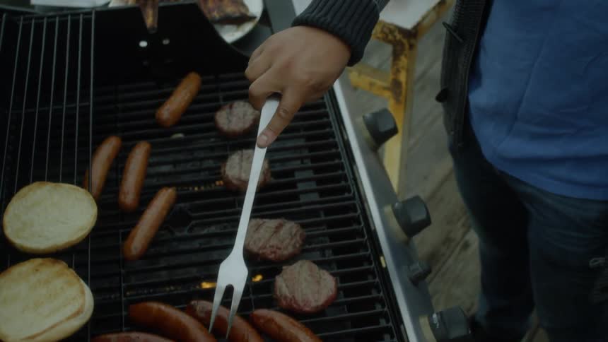 A man grills hamburgers and hotdogs