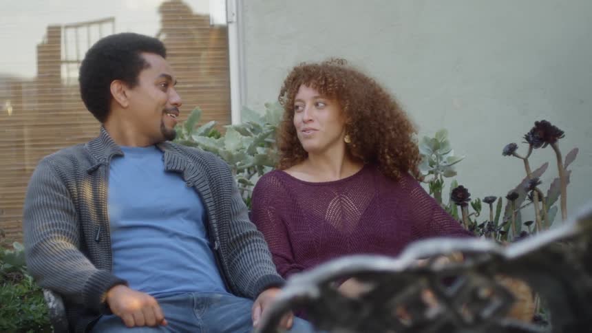 Man and woman sitting outside are talking and laughing