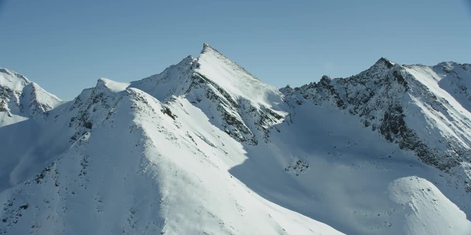 Snow is covering the peaks of a mountain range during the day