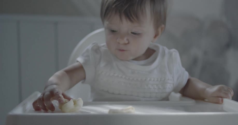 A child is sitting in a high chair reaching forward