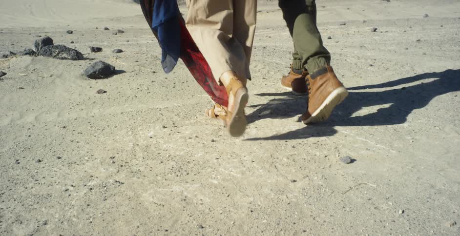 Woman and man walk across desert floor