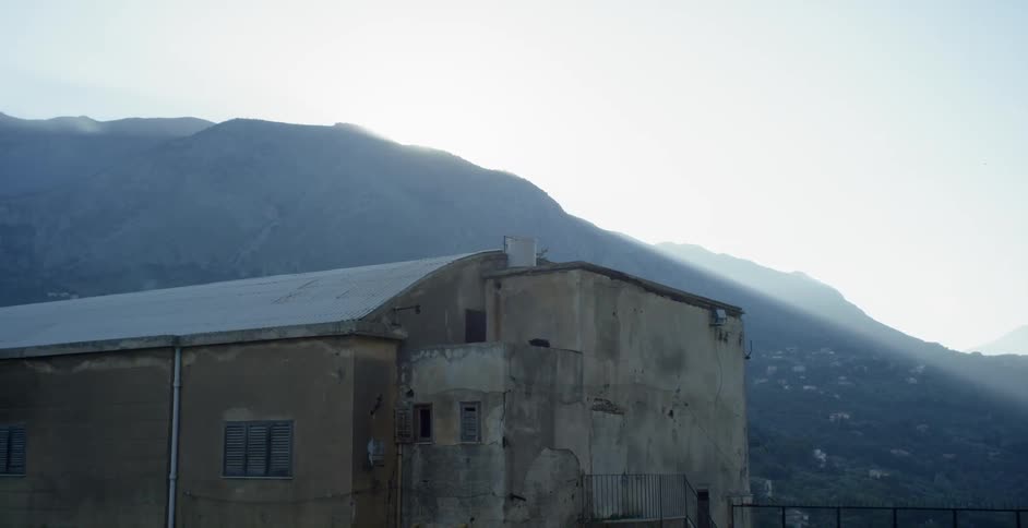 Old building sitting before mountains on a cloudy day