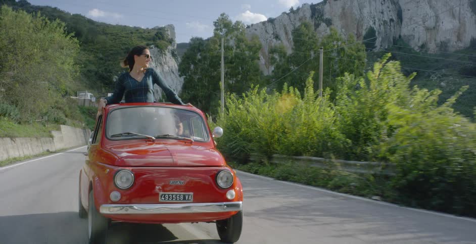 Woman rides out of the top of a small red vehicle