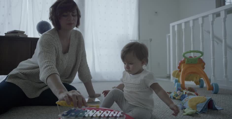 A woman is playing with a baby on the floor