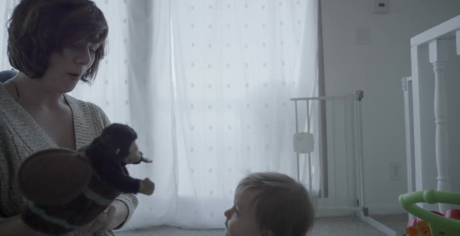 Woman playing with puppet toy in nursery room with baby