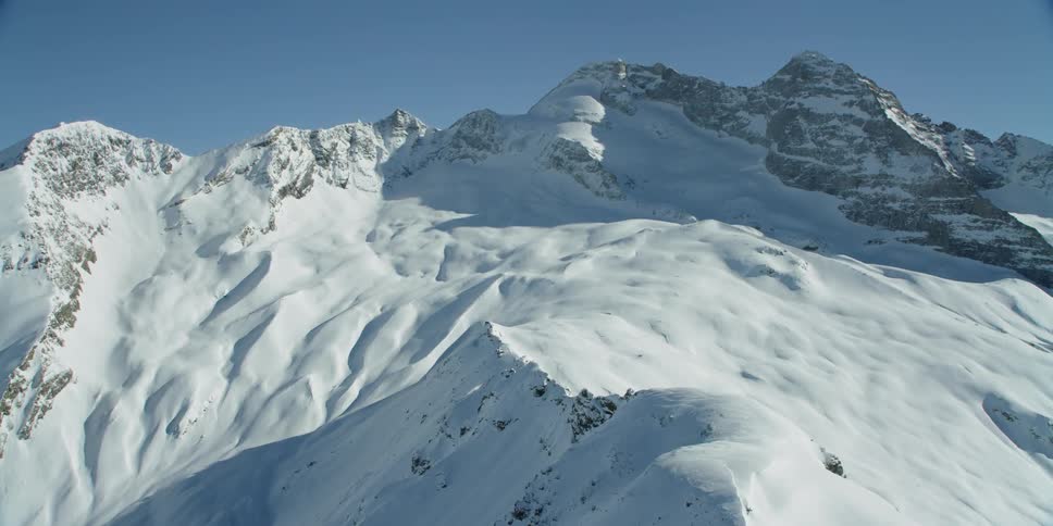 Snow is covering the slopes of a mountain range during the day