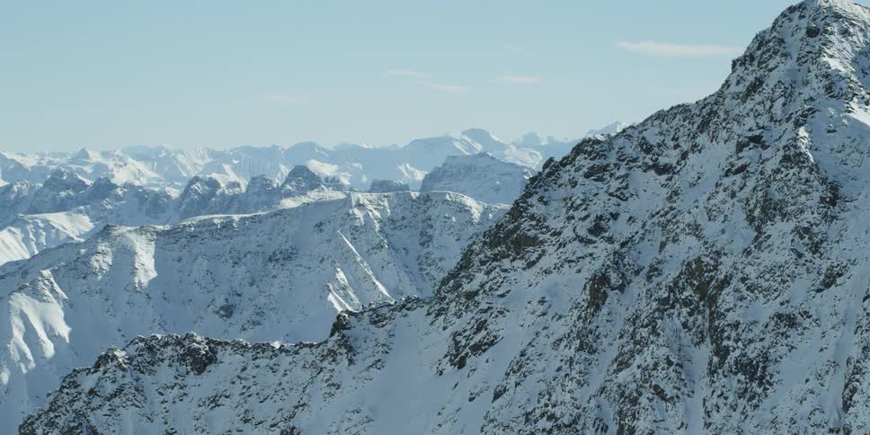 Snow is covering the slopes of a mountain range during the day